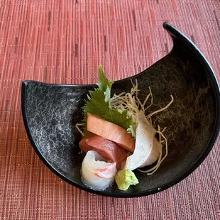 a black bowl with sushi and vegetables