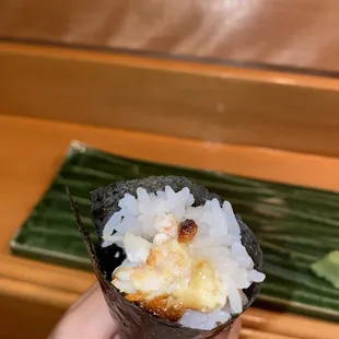 a person holding a piece of sushi
