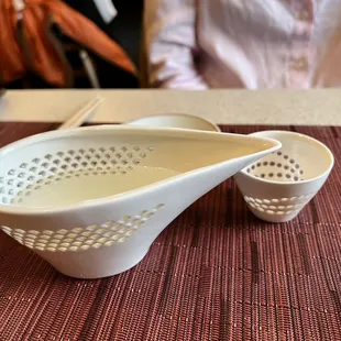 a person sitting at a table with a bowl and two spoons