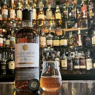 a bottle of whisky and a glass on a bar