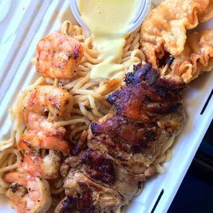 Shrimp skewers, chicken skewers, crustacean cream cheese puffs over garlic noodles.