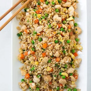a plate of fried rice with chopsticks