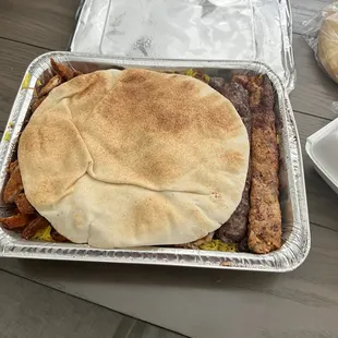 a pita sandwich in a foil container