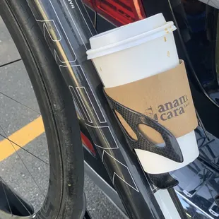 a cup of coffee on the handle of a bike