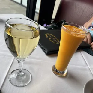 a glass of white wine and a glass of orange juice