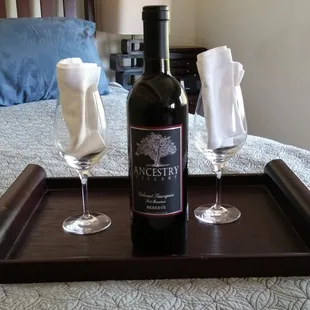 two wine glasses and a bottle of wine on a bed