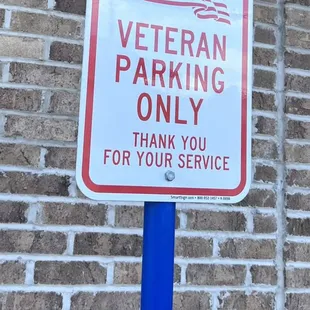 a no parking sign in front of a brick wall