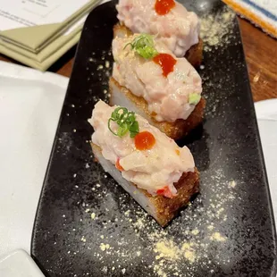 two pieces of crab cake on a black plate