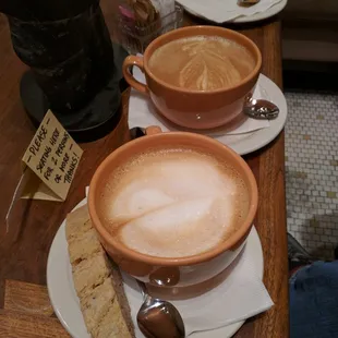 Grande wet cappuccino with walnut anise biscotti in front and a grande latte behind.