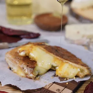 a grilled cheese sandwich being drizzled with honey