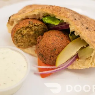 a pita sandwich with a side of dip