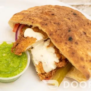 a pita sandwich with a side of guacamole
