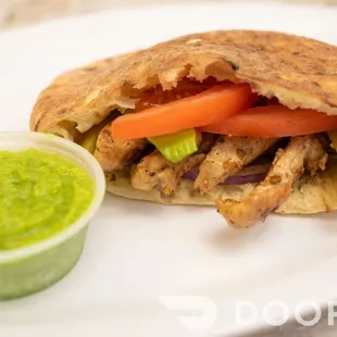 a pita sandwich with a side of guacamole