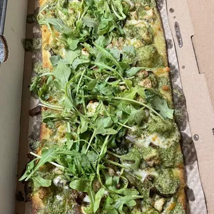 Pesto sauce, mushrooms, grilled onions, basil, shredded mozzarella, chicken, arugula, and basil drizzle