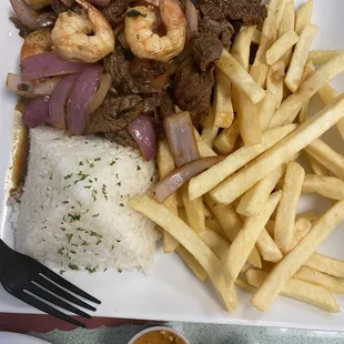 a plate of rice, meat, and fries