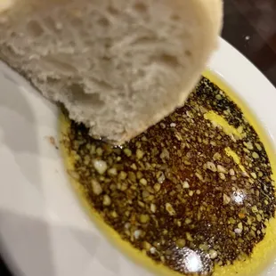 a piece of bread being dipped with olive oil