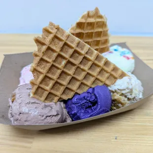 Sampler Flight. $7.75. Baklava, Cake Batter, Oreo Latte, Ube, Malted Twix, Rose Pistachio. Topped with 2 waffle wedges.