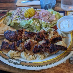 2 chicken skewers, with rice, pita bread, taziki sauce, and Greek salad