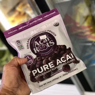 a hand holding a bag of pure acai