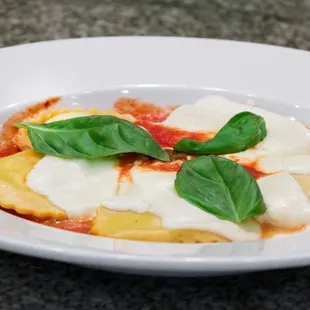 a plate of ravierole with cheese and basil leaves