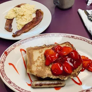 a plate of french toast with strawberries and bacon