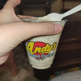 a hand holding a cup of ice cream