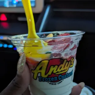 a hand holding a cup of yogurt