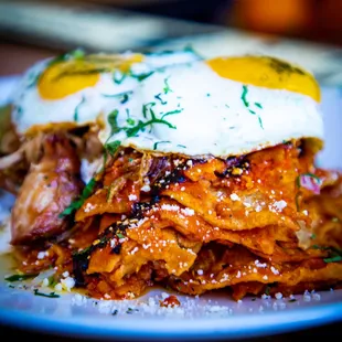 Chilaquiles Divorciados with red and green sauce, red onion, cilantro, cotija cheese and fried eggs.