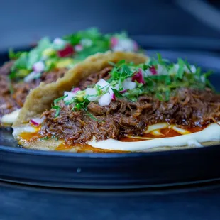 Barbacoa Tacos with melted Oaxaca cheese, pinto beans, tomatillo salsa, cilantro and red radish.