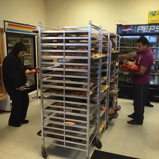a man and a woman standing in front of a rack of baked goods