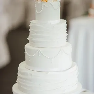 a white wedding cake with orange roses