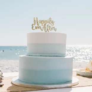 a three tiered cake on a table on the beach