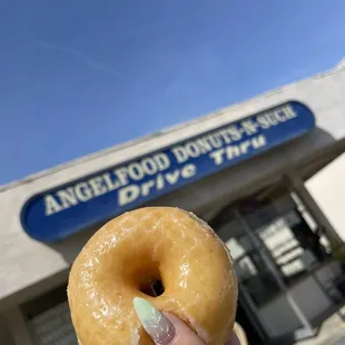 a hand holding a glazed donut