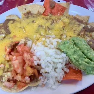 Bean and cheese nachos with tomato, onion and guacamole added.