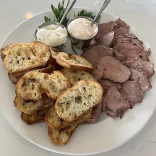 Beef Tenderloin Crostini | Tender sliced beef served on house made crostini with a side of horseradish sauce &amp; bleu cheese dressing.