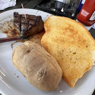 Steak, baked potato, and garlic bread