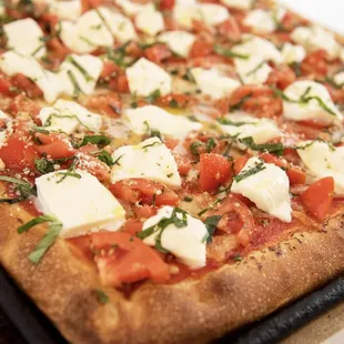 a pizza with tomatoes, mozzarella, mozzarella, cheese, and