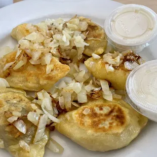 Mixed variety of perogies with grilled onions and sour cream.