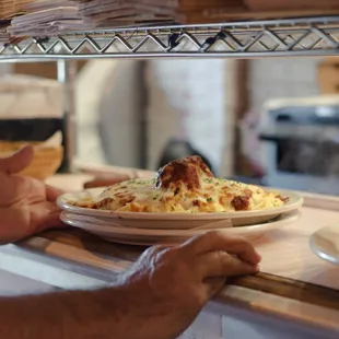 Spaghetti and meatballs topped with melted mozzarella cheese.