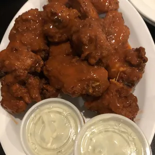 a plate of chicken wings with dippings