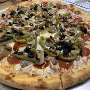 a pizza with pepperoni, mushrooms, olives, and peppers
