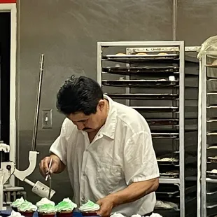 a man decorating cupcakes