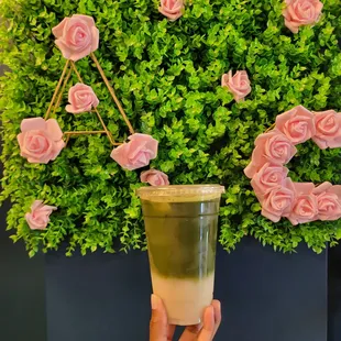 a hand holding a cup of green tea