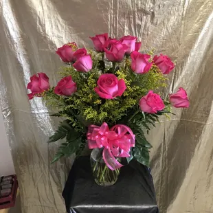 Pink dozen roses in a vase. Pink roses, solidago, leatherleaf, pink bow, glass vase.