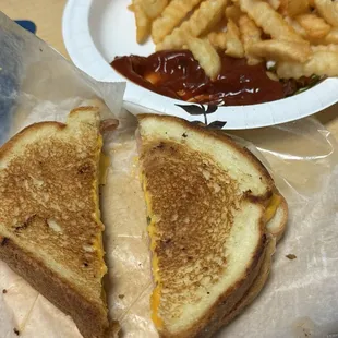 Grilled cheese and ham sandwich, with French fries.