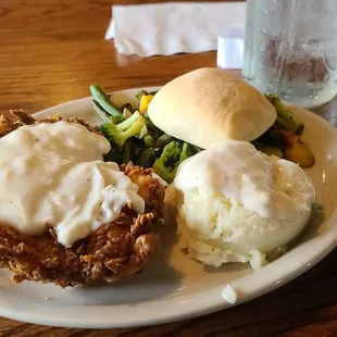 Chicken fried chicken with grilled veggies mashed potatoes and roll.