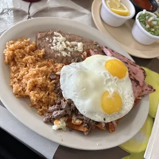 Chilaquiles with carne asada piece of ham &amp; sunny side up eggs