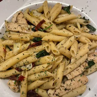 a plate of pasta with chicken and spinach