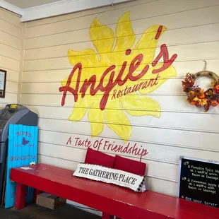 a red bench in front of a painted sign