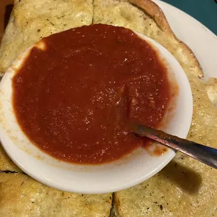 a bowl of tomato sauce and pita chips